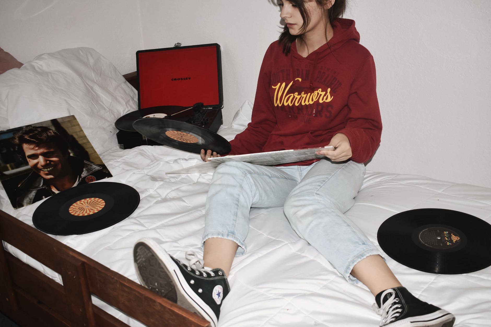 woman sitting on bed holding vinyl records